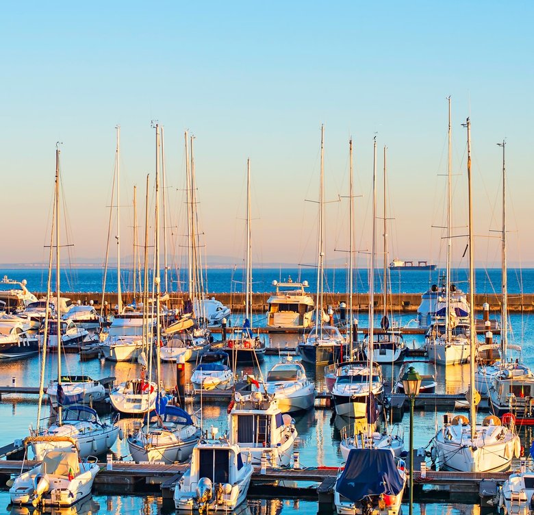 Sailboats moored in the marina at golden hour
